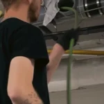 Technician feeding auger cable into overhead cleanout to clear main drain.