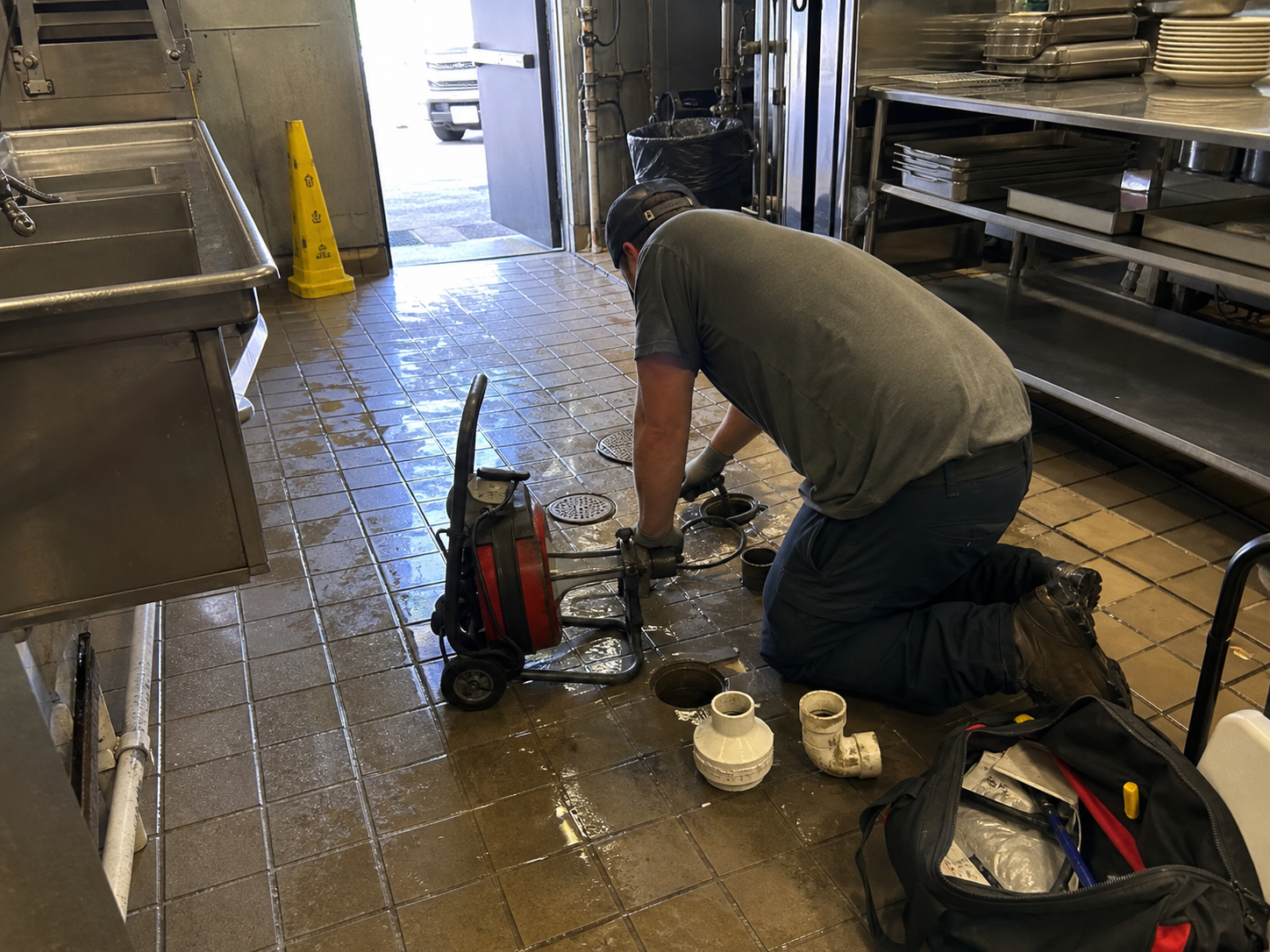 Plumber working on an emergency commercial kitchen grease drain backup